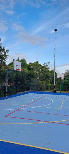 A basketball court with trees in the background
Description automatically generated