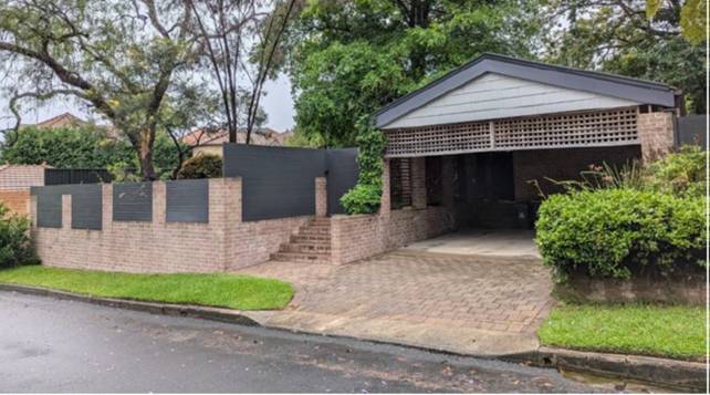 A house with a brick wall and a fence
AI-generated content may be incorrect.