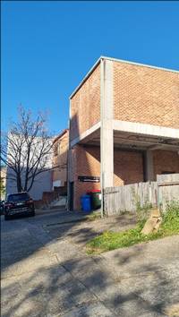 A brick building with a fence and a car parked in front of it

AI-generated content may be incorrect.